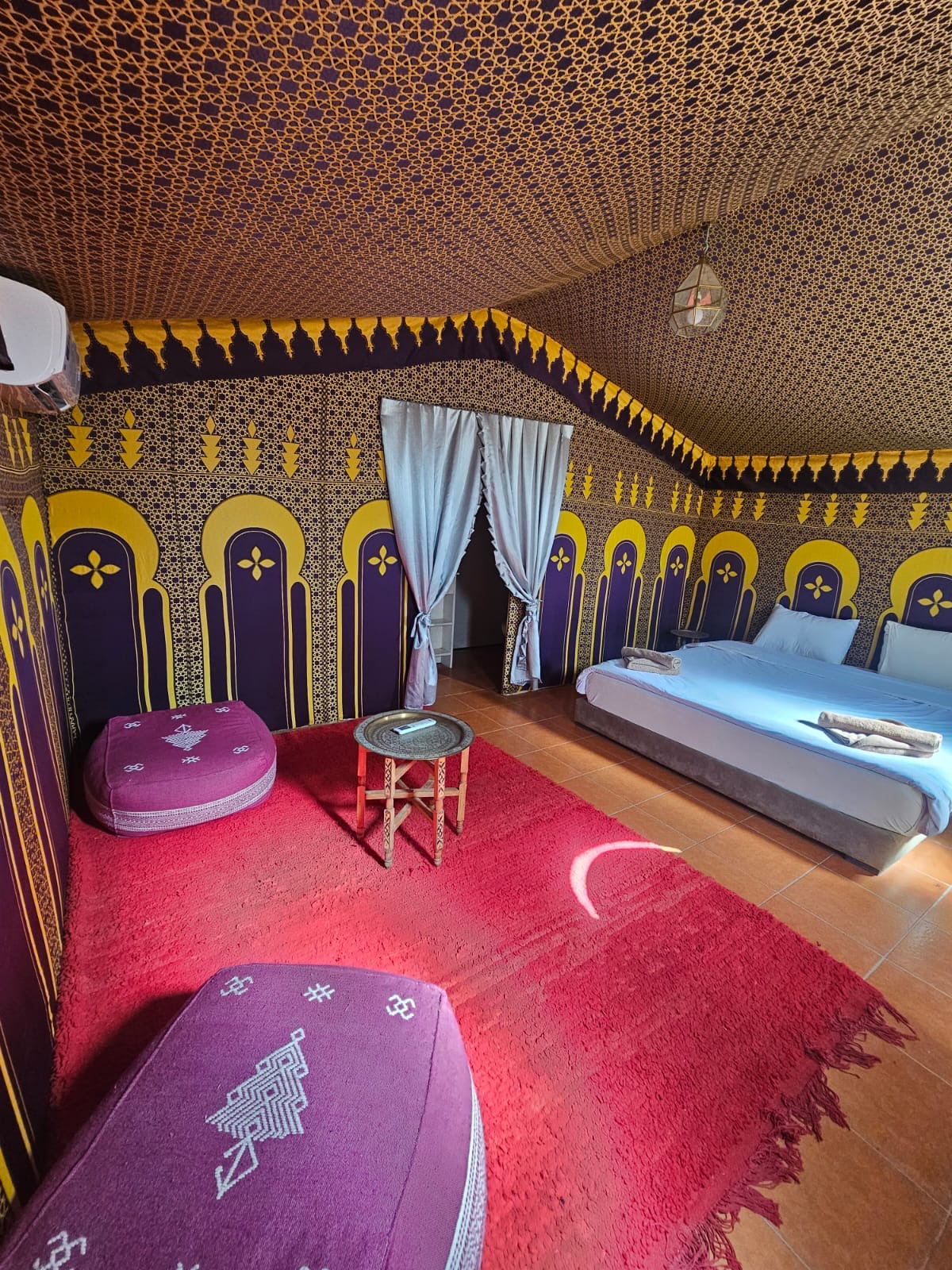 Grande tente berbère avec lit et tapis rouge
